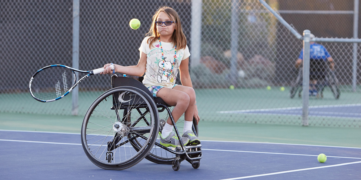 Young female youth wheelchair player hitting a ball.