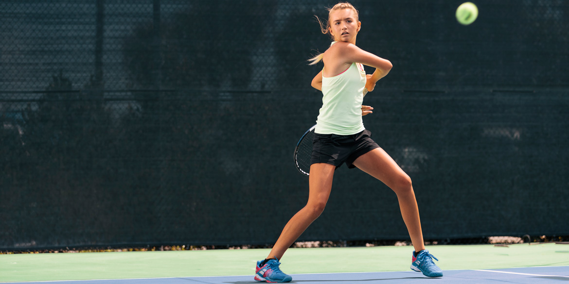 Teen athlete swinging a racquet at tennis ball Teen athlete swinging a racquet at tennis ball