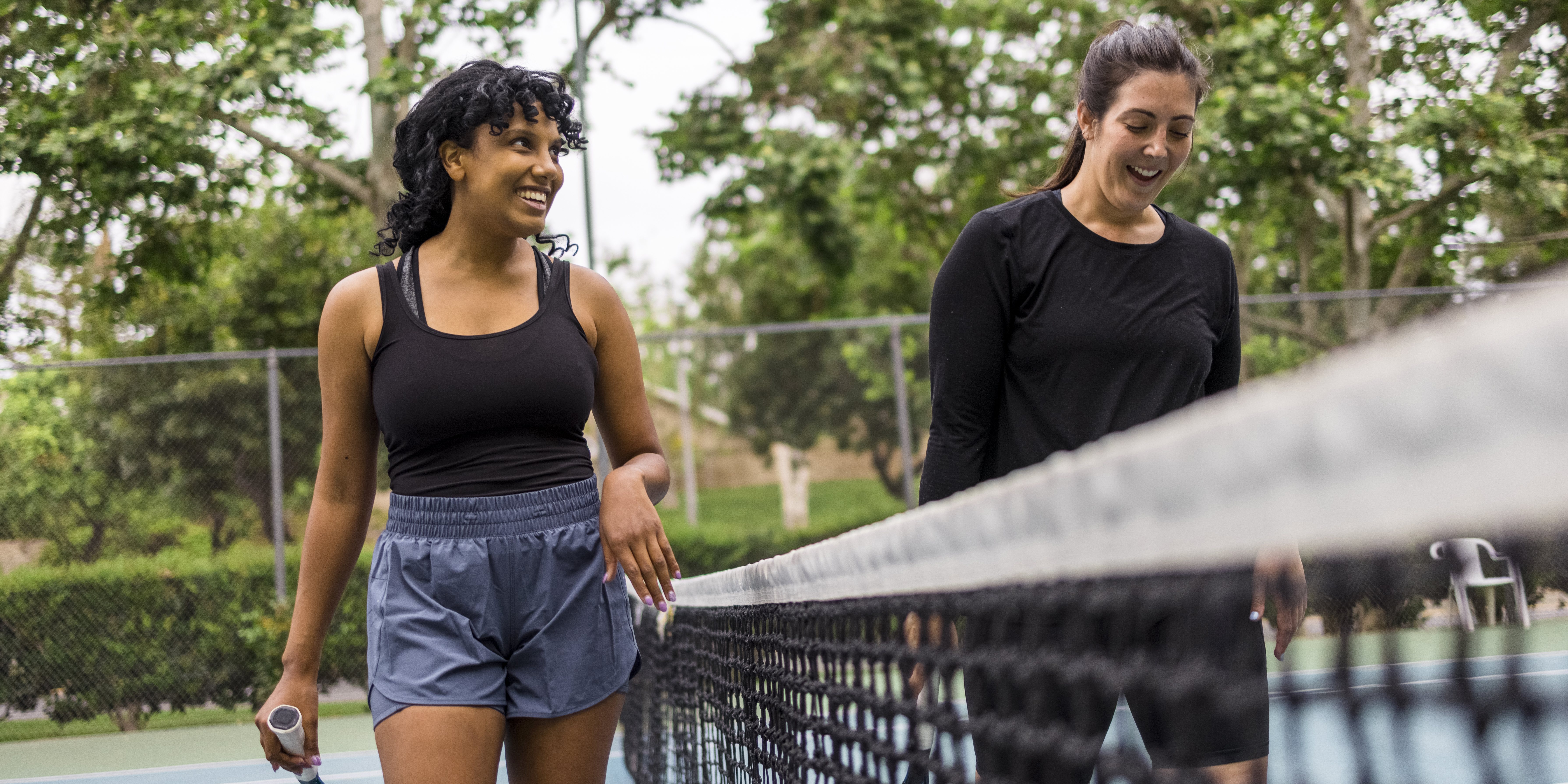 A young black woman and her mother playing tennis