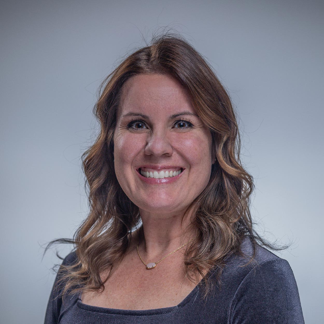 Allison Davis smiles for a photo against a gray background.