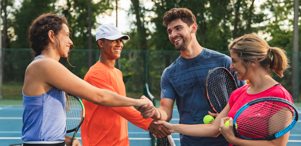 Four tennis players shaking hands over the net after playing a match showing sportsmanship