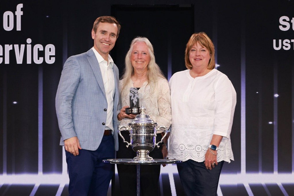 Three recipients of the USTA Adaptive Tennis Award holding a trophy in front of a black background