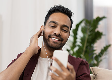 Man with headphones on watching a video on cellphone.