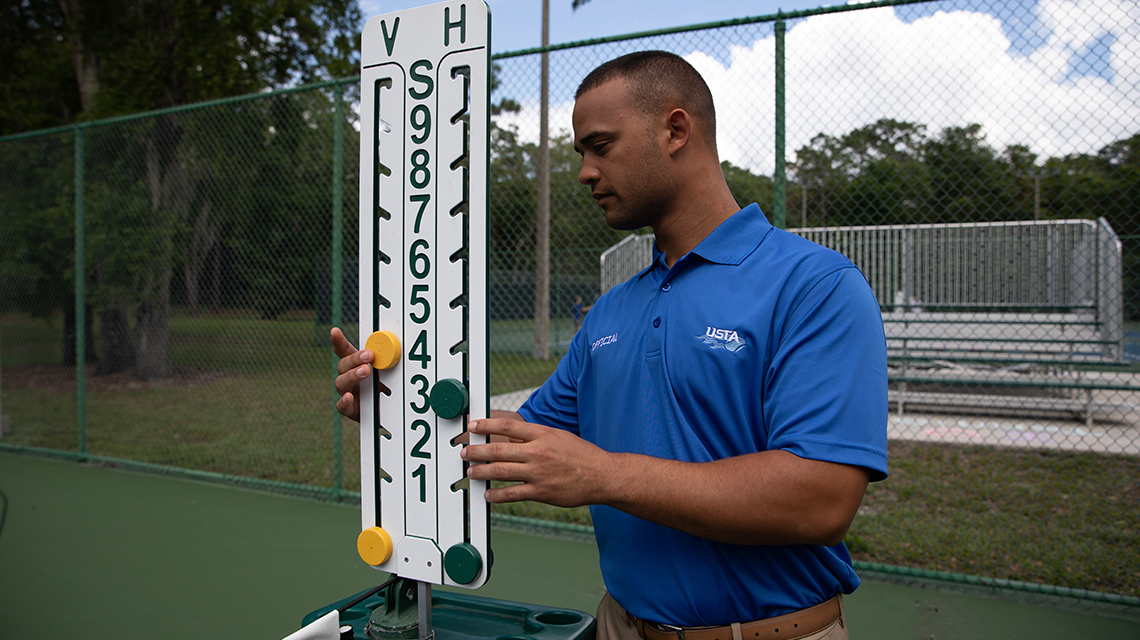 USTA referee keeping score on a sign, highlighting the unique point system used in tennis games.