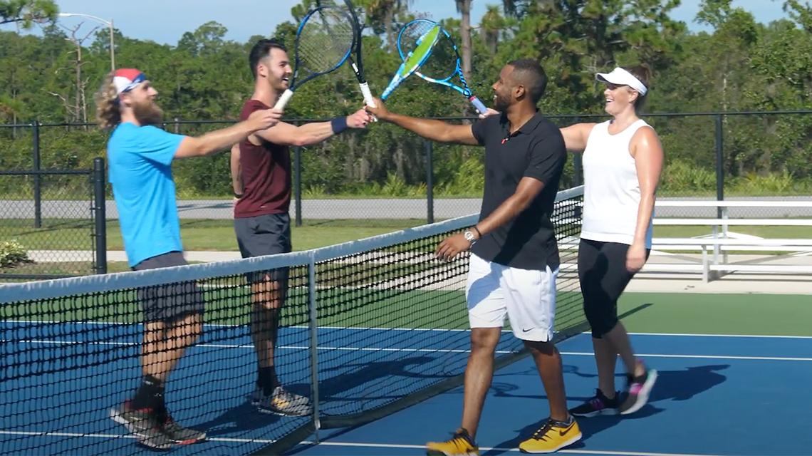 Four men tapping racquets at the net after a doubles match, representing tennis scoring rules for games, sets, and ties.