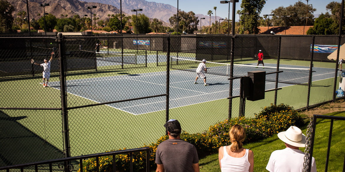 People playing tennis while some people watch