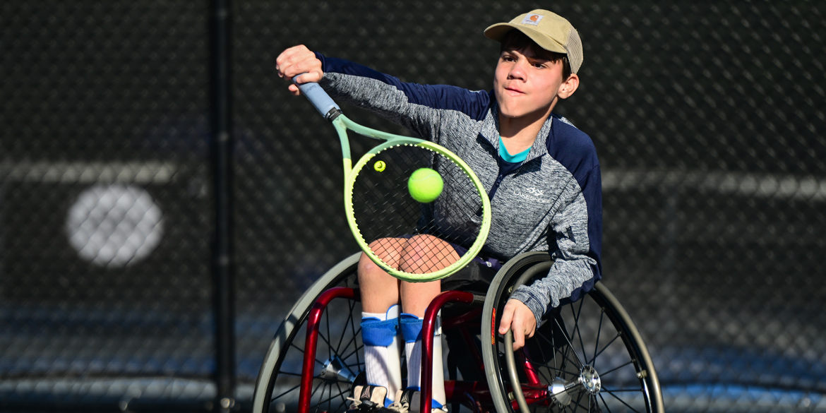 A young wheelchair tennis player playing in a junior wheelchair tennis tournament 