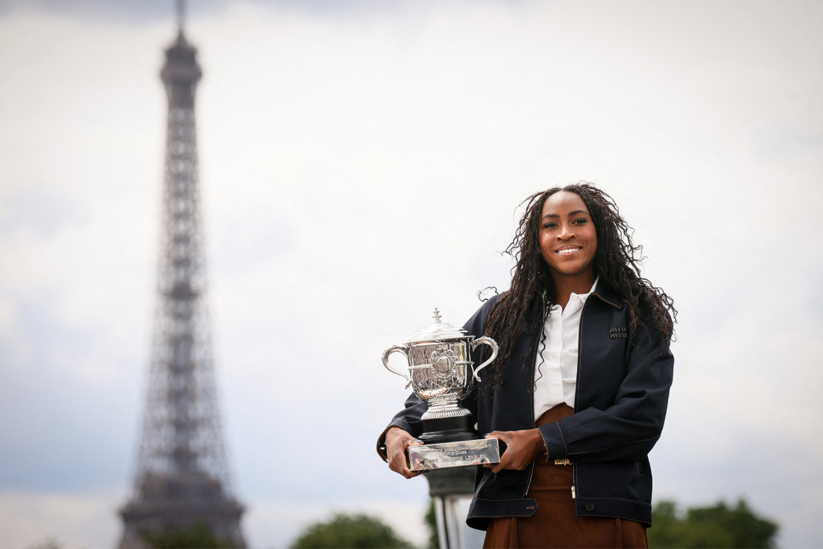 Coco Gauff poses with the French Open trophy with the Eiffel Tower in the background.