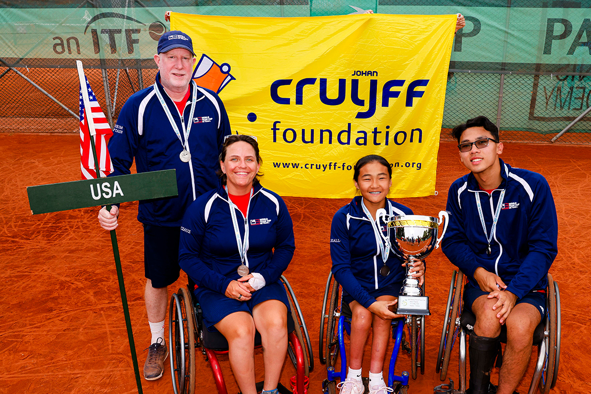 Three players in wheelchairs pose for a photo with their coach.