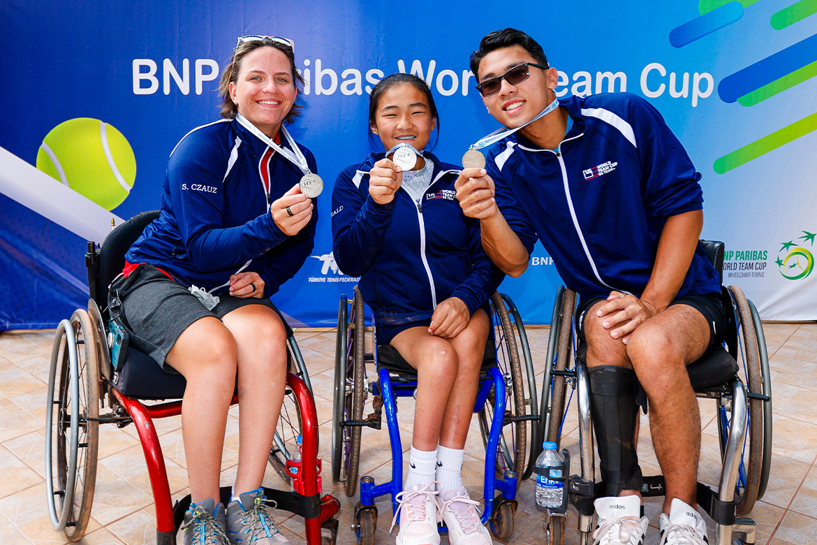 Three players in wheelchairs hold silver medals.